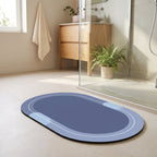 Alfombra de baño azul ovalada frente a la ducha en un baño luminoso.