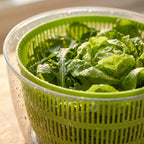 Detalle de hojas de lechuga con gotas de agua dentro del canasto verde ranurado.