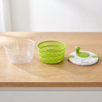 Las tres piezas de la centrifugadora separadas: bowl transparente, canasto verde y tapa con manivela.