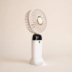 Ventilador portátil blanco con pantalla y base, sobre fondo blanco hueso.