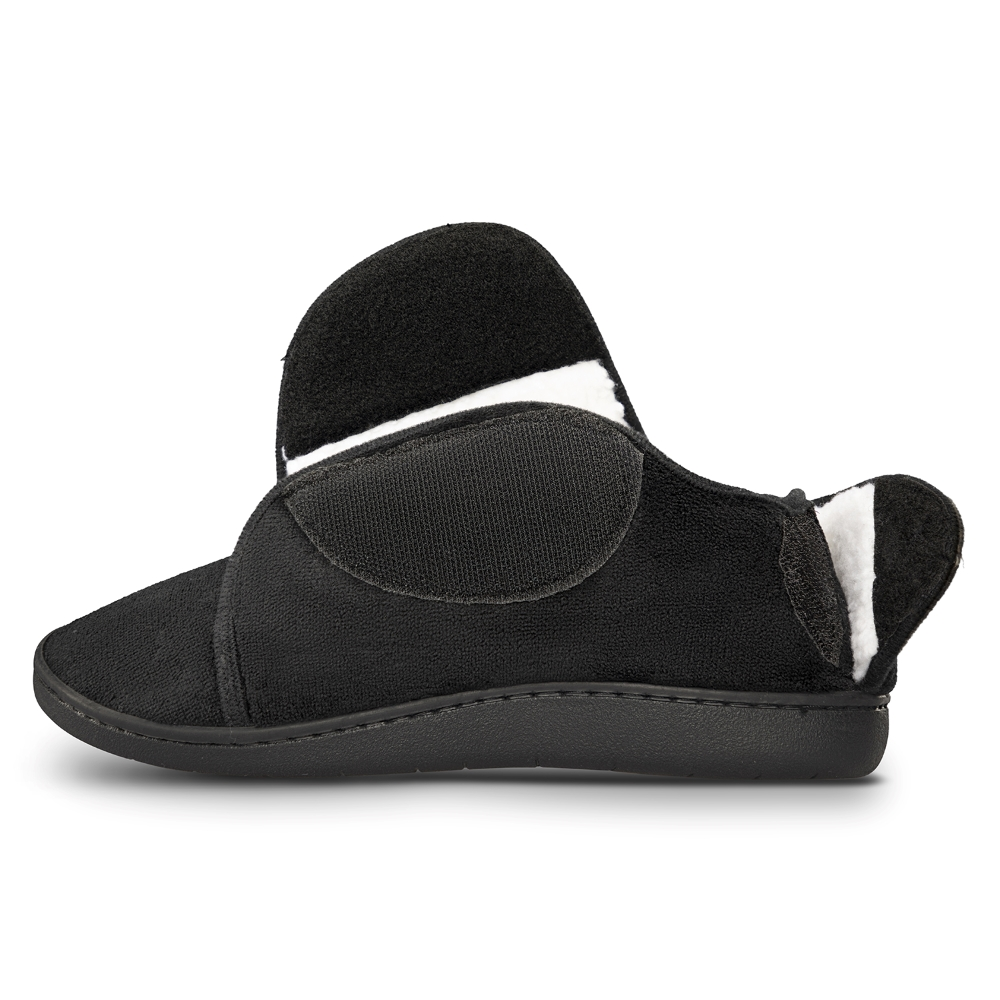 Pantufla negra de perfil con la solapa abierta, mostrando el velcro y el ribete de borrego blanco.