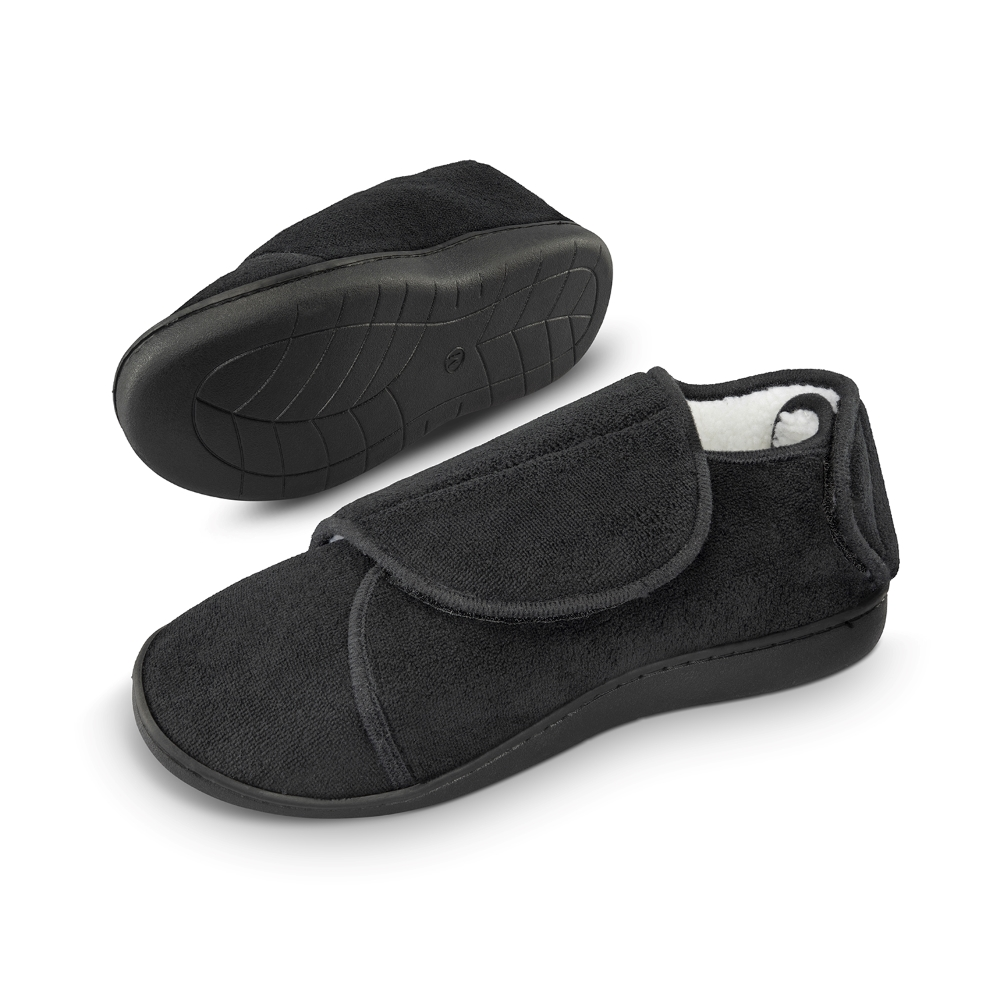 Par de pantuflas Comfy Wraps negras sobre fondo blanco, una volteada mostrando la suela antideslizante.